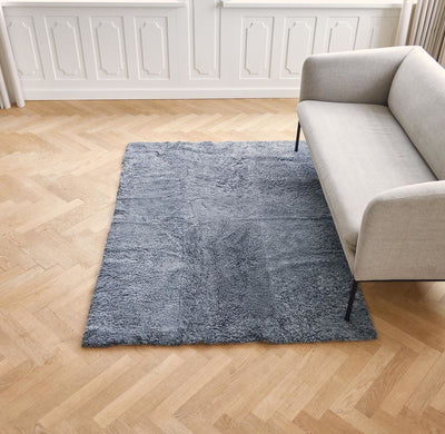 Designer Teppich aus Lammfell vor einem Sofa
